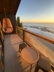 a balcony with a table and chairs on the beach at Rukamar Cocholgue in Tomé