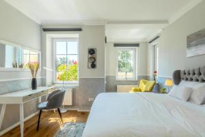 a bedroom with a bed and a desk and windows at Boutique Hotel Villa Wahnfried Thiessow in Thiessow
