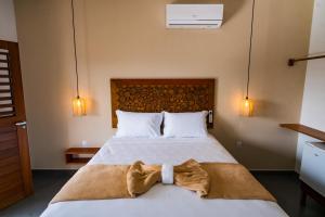 a bedroom with a bed with two towels on it at Pousada Brisa do Cardeiro in São Miguel do Gostoso