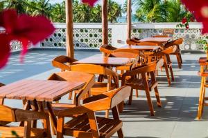 a row of wooden tables and chairs on a patio at Pousada Brisa do Cardeiro in São Miguel do Gostoso +8 photos
