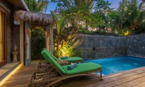 a patio with a pool and a green lounge chair next to a swimming pool at Sari Dana Villas in Sanur