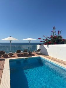 a swimming pool with chairs and umbrellas at Apartamentos Rossio Mar in Albufeira