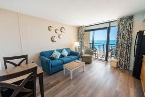 a living room with a blue couch and a balcony at Amazing Oceanfront Accessible Beach Amazing View in Myrtle Beach
