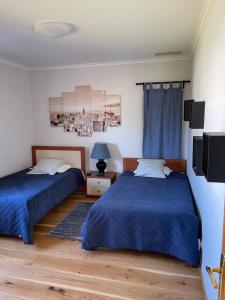 two beds in a bedroom with blue sheets and a tv at Lagoa House Albufeira in Lagoa de Albufeira +60 photos