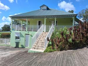 a green house with stairs in front of it at Villa Greg in Bouillante