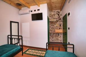 two beds in a room with a tv on the wall at Alchemist Inn in Gjirokastër