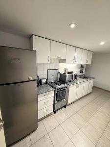 a kitchen with white cabinets and a stainless steel refrigerator at Depto. PREMIUM Barrio Norte in San Miguel de Tucumán