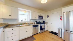 a kitchen with white cabinets and a sink and a refrigerator at Dog Friendly Oceanfront Home with Hot Tub & Views in Fort Bragg