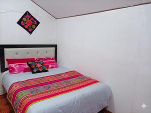 a bedroom with a bed with pink and colorful sheets at Uros titikaka Golden Lodge in Puno