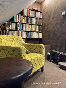 a library with a yellow couch and a book shelf with books at Cottage Scandi Dedinky in Dedinky