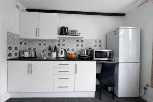 a kitchen with white cabinets and a refrigerator at Self-contained Studio Slough, Berkshire in Canvey