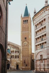 a tall tower with a clock on a building at HOUSE Cavour 24 In the heart of Downtown Parma in Parma