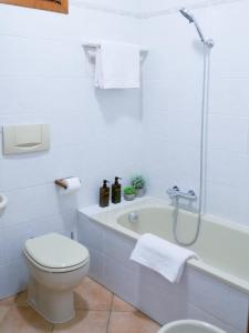 a white bathroom with a toilet and a bath tub at Il nido di Lera in Lenno +8 photos
