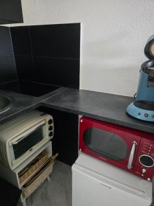 a red microwave sitting on top of a kitchen counter at Le Stud in Belfort