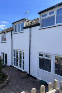 a white house with doors and windows at 3 Harbour Lights, Newlyn in Penzance