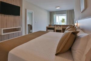 a bedroom with a large bed and a desk at Itapema Beach Hotel & Convention in Itapema +38 photos
