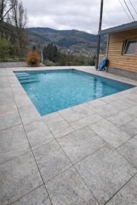 a swimming pool with a tile floor and a house at Le Chalet des 5 avec piscine vue sur les montagnes et en lisière de forêt in Lutzelhouse