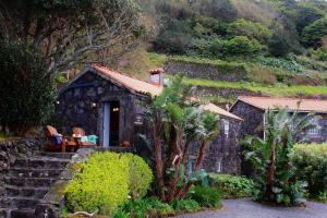 a stone cottage with a table and chairs in front of it at Casa do Laureano in Santo Amaro