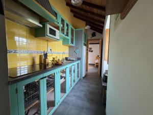 a kitchen with green cabinets and yellow tiles at Casa do Laureano in Santo Amaro