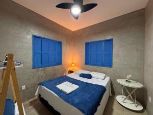 a bedroom with a bed with blue windows and a table at Casa Cações Beach Marataizes in Marataizes +64 photos