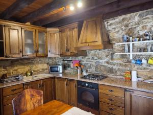 a kitchen with wooden cabinets and a stone wall at Sintra Knights Lodge in Terrugem