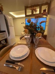 a table with white plates and a vase of flowers at Casa Lima Premium in Arapiraca
