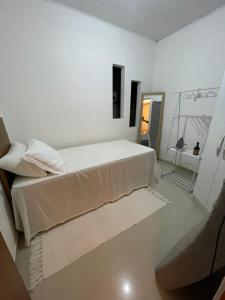 a white bedroom with a bed and a mirror at Casa Lima Premium in Arapiraca +2 photos