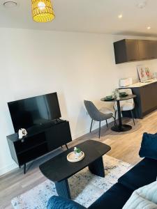 a living room with a couch and a tv and a table at Stylish Modern 1-Bed Apartment in Manchester