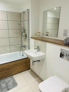 a bathroom with a sink and a toilet and a tub at Stylish Modern 1-Bed Apartment in Manchester