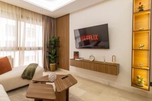 a living room with a television on a wall at Appartement Uptown CFC - Piscine - Gym - Parking Gratuit in Casablanca