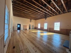 a large room with a wooden floor and windows at Monticello Inn & Cottage in Scottsville