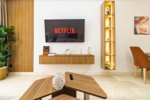 a living room with a tv on a wall at Appartement Uptown CFC - Piscine - Gym - Parking Gratuit in Casablanca +28 photos
