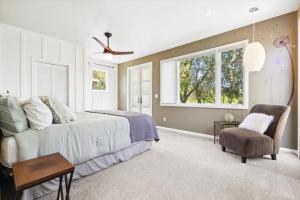 a bedroom with a bed and a chair and windows at Bennett Valley Eden in Santa Rosa