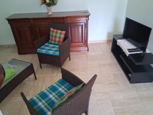 a living room with chairs and a table and a tv at Villa Greg in Bouillante