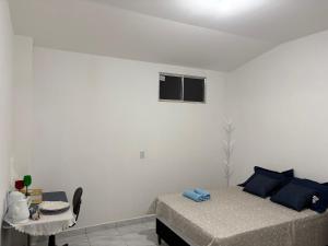 a bedroom with a bed with blue pillows and a table at Studio suite casal in Teresina