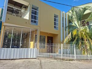 a building with a white gate and a palm tree at Tulip House in Comayagua