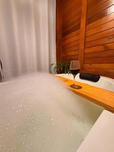 a bath tub filled with water with a glass of wine at Cabana Zanetti in Santa Teresa