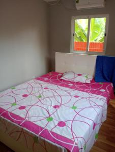 a bed with a pink and white comforter and two windows at Holiday Home T3 to T6 on suite in Amparo II