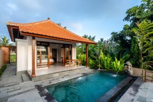 a villa with a swimming pool in front of a house at Taru Sebatu Villa in Ubud