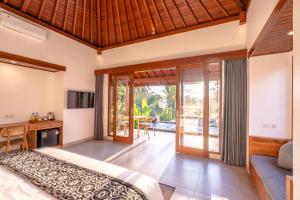 a bedroom in a villa with a bed and a desk at Taru Sebatu Villa in Ubud