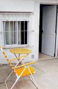 a yellow table and a chair in front of a garage at Lo de Liliana 1 in Tanti