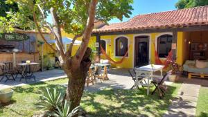a yellow house with tables and chairs in a yard at Chill House Buzios in Búzios