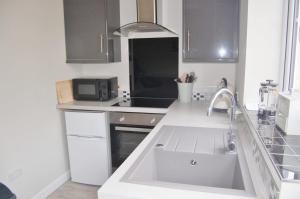 a white kitchen with a sink and a microwave at Gig Lodge Perfect Swanage Base in Swanage +7 photos