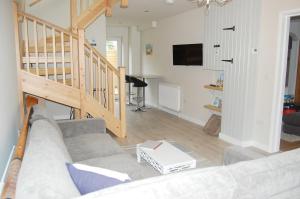 a living room with a couch and a staircase at Gig Lodge Perfect Swanage Base in Swanage