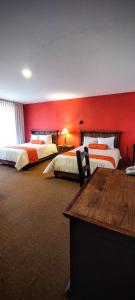 a hotel room with two beds with red walls at La Huerta golf & hotel in Cholula