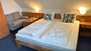 a hotel room with two beds and a chair at Hotel Relax in Wachenroth
