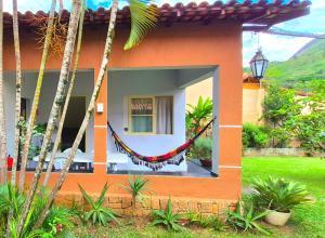 a house with a hammock in front of it at Suítes Colibri da Serra - Piscina & Conforto em Itaipava RJ in Itaipava