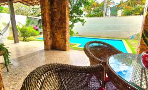 a patio with a table and chairs next to a pool at Suítes Colibri da Serra - Piscina & Conforto em Itaipava RJ in Itaipava
