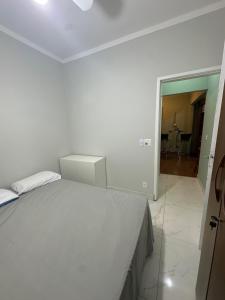 a white bedroom with a bed and a room with a table at Quarto com banheiro in Sao Jose do Rio Preto