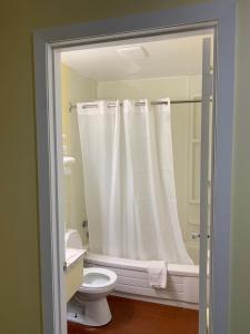a bathroom with a white shower curtain and a toilet at Spanish River Inn in Spanish